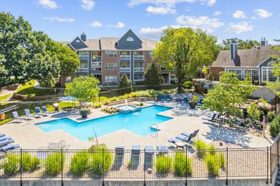 A large swimming pool surrounded by a fence and chairs.