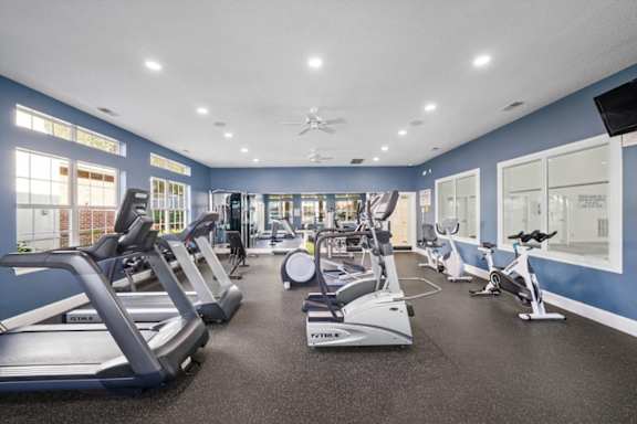 A spacious gym with treadmills, elliptical machines, and other exercise equipment.at The Claremont Apartment Homes, Overland Park, 66210
