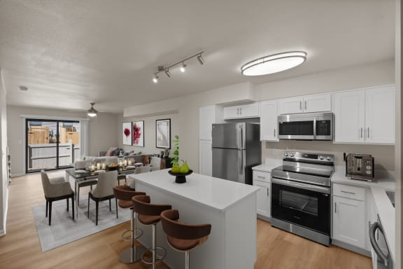 furnished kitchen and dining room with stainless steel appliances and a white kitchen island with chairs