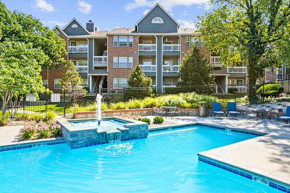 A beautiful swimming pool with a fountain and lush landscaping at Stonebriar Apartments in Overland Park, KS.