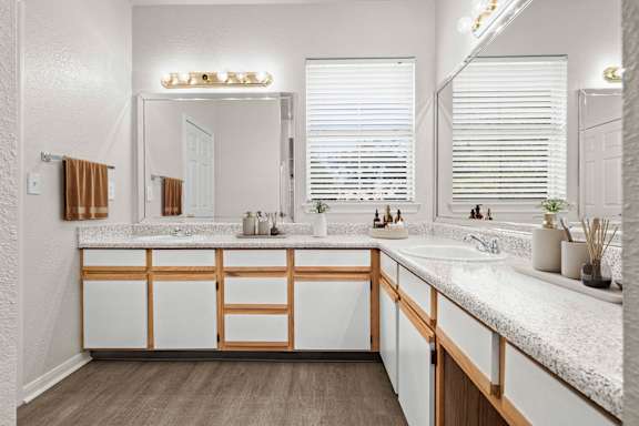 A large bathroom with large vanity mirrors, a window, lots of storage cabinets, and lots of counterspace.