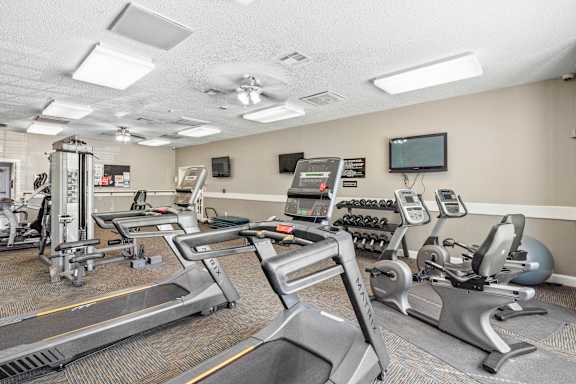 A gym with treadmills, weights, and exercise equipment.