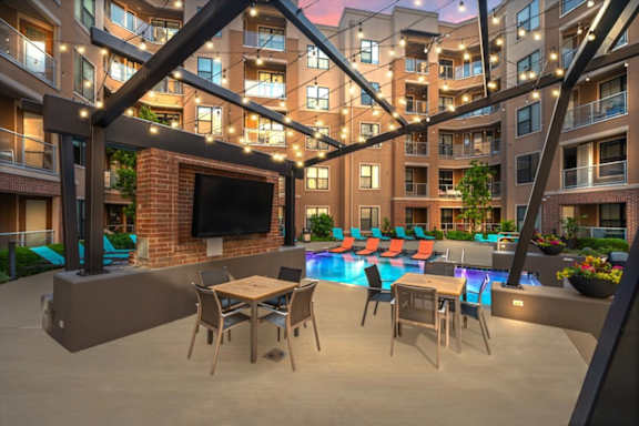 A patio area with a table and chairs is surrounded by apartment buildings.