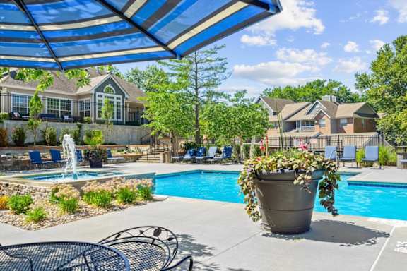 A pool area with a fountain and a patio umbrella.