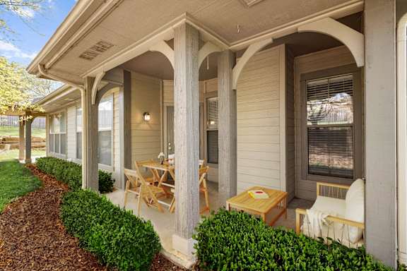 A private patio with columns and green bushes.
