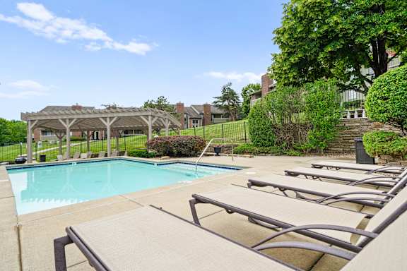 A pool with sun loungers and a pavilion in the background. at Coventry Oaks Apartments, Kansas, 66214