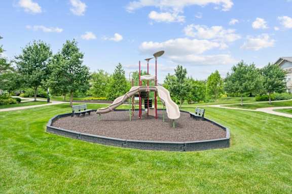 A playground with a slide and a red pole. at Stonepost Crossing Apartments, Overland Park