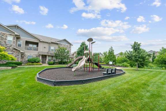 A playground with a slide and a basketball hoop. at Stonepost Crossing Apartments, Kansas