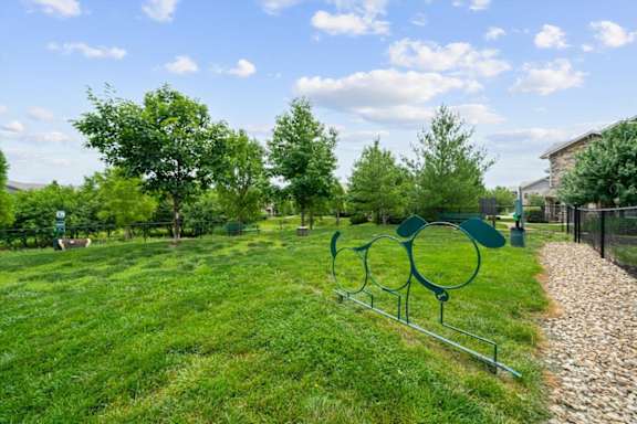 A green park with a sculpture of three circles. at Stonepost Crossing Apartments, Overland Park, KS, 66213