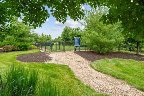 A sign is in a fenced area with a gravel path leading to it. at Stonepost Crossing Apartments, Overland Park, 66213