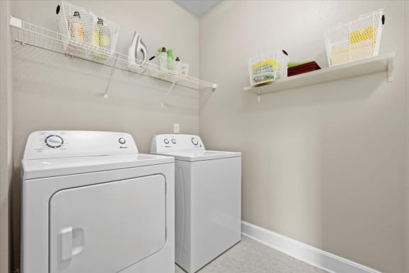a white washer and dryer in a laundry room with shelves