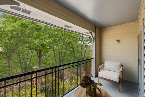 a balcony with a chair and a view of the woods at Crescent Apartment Homes, Lenexa, KS
