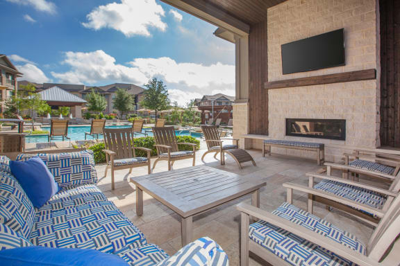 outdoor living area with chairs tv and fireplace at Ovation at Lewisville Apartments, Lewisville