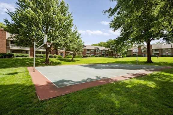 Outdoor basketball court at Highland Park Apartment Homes surrounded by landscaped grounds and residential buildings.