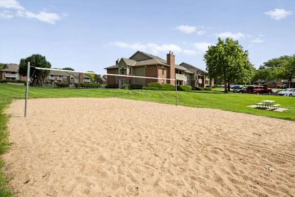 Sand volleyball court at Highland Park Apartment Homes with surrounding residential buildings.