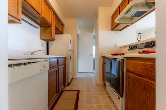 Kitchen with appliances, wooden cabinets, sink and granite counter topsat Coventry Oaks Apartments, Overland Park