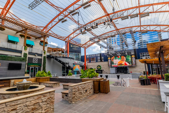 a view of the outdoor seating area with a water fountain in the foreground and a large screen