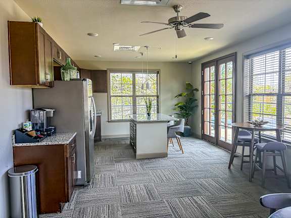 Rooftop lounge at The Dorset Apartments with coffee station, dining tables, and access to outdoor terrace through French doors.