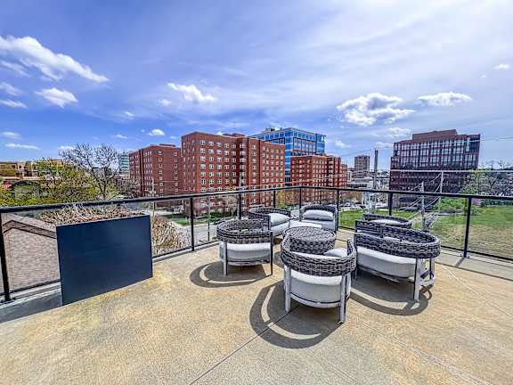Skyline view from rooftop terrace at The Dorset Apartments with outdoor circular lounge seating and glass railing.