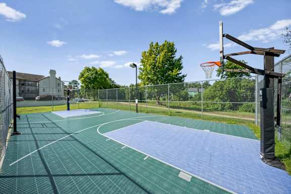 Fenced outdoor basketball court with a well-maintained playing surface at Millcreek Woods Apartment Homes.