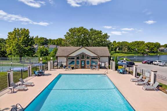 Outdoor swimming pool with lounge seating and lake views at Millcreek Woods Apartment Homes.