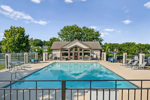 Resort-style swimming pool with lounge chairs and the community clubhouse in the background.
