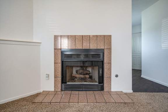 Tile-surround fireplace in a Millcreek Woods apartment home living area.