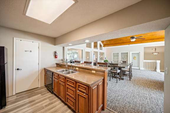 Open clubhouse kitchen with ample counter space and adjacent resident gathering area.