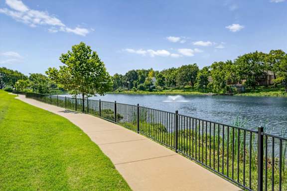 Paved walking trail along the community lake with waterfront views and green space.
