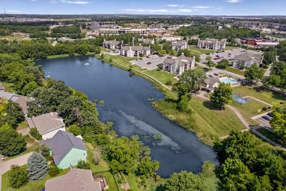 Drone view of the community lake, residential buildings, walking paths, and amenities.