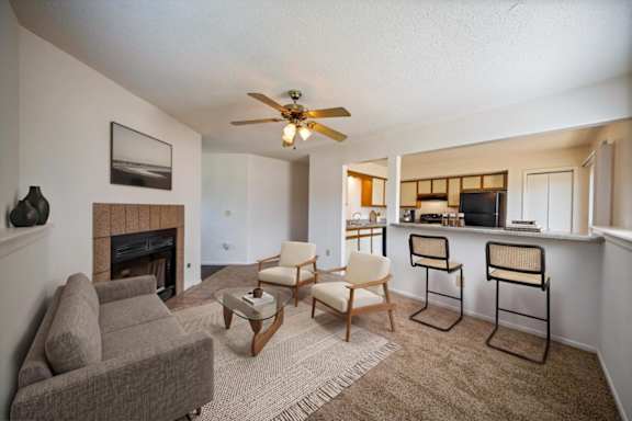 Open-concept living room featuring a fireplace, breakfast bar seating, and adjacent kitchen.