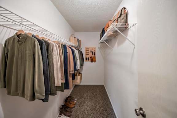 Extended walk-in closet with hanging rods, shelving, and additional storage space.