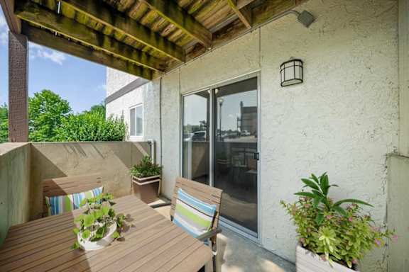 Covered patio featuring outdoor dining furniture, decorative planters, and sliding glass door access.