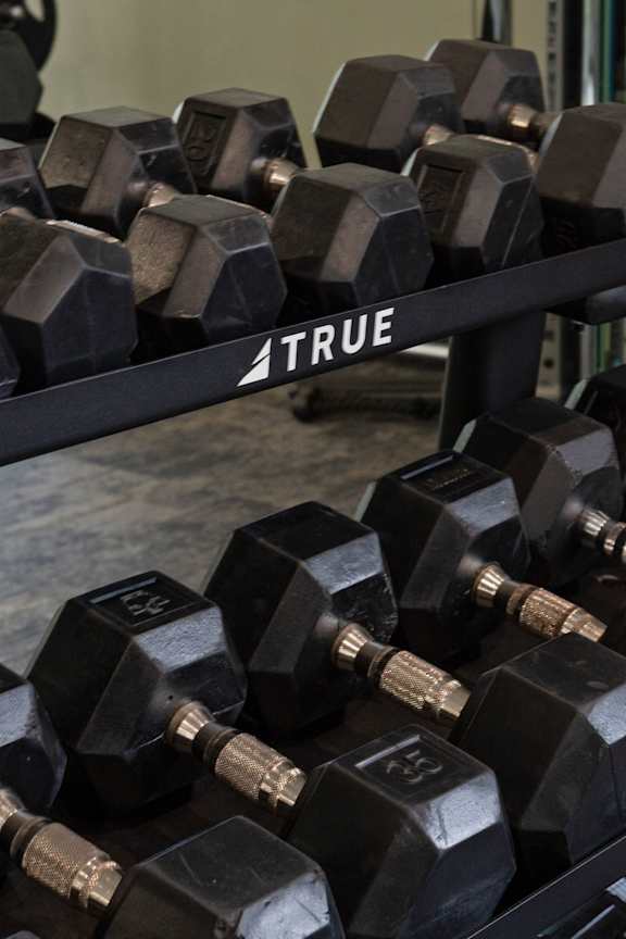 A set of black TRUE dumbbells are on a rack.
