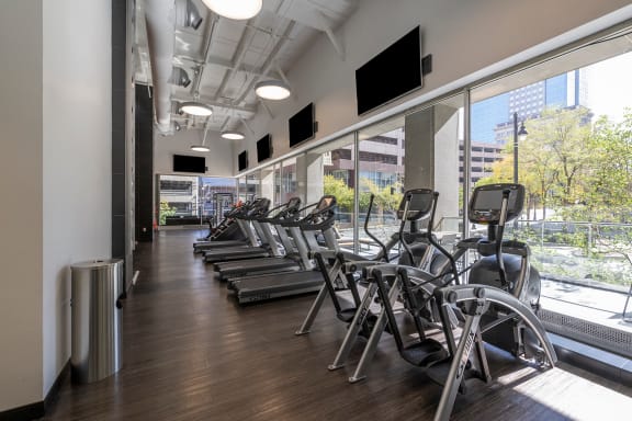 a row of cardio machines in a fitness room with a large window at Sky on Main, 64105