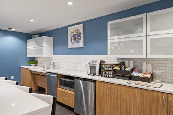 Resident coffee bar at Sky on Main featuring complimentary coffee service, modern cabinetry, countertop seating, and stainless steel appliances.