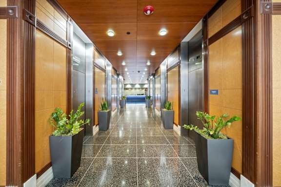 Elevator lobby at Sky on Main with polished flooring, wood-paneled walls, decorative plants, and modern lighting.