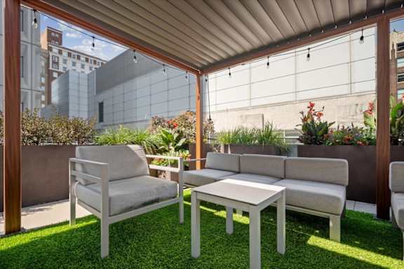Rooftop pergola lounge at Sky on Main featuring cushioned seating, landscaped planters, and outdoor social space.