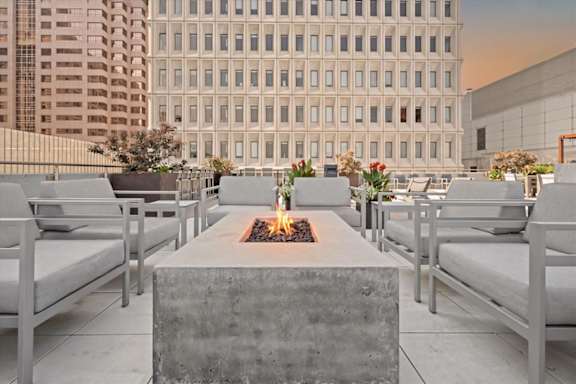 Rooftop lounge at Sky on Main with outdoor seating arranged around a fire pit and views of Downtown Kansas City.
