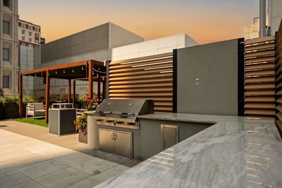 Outdoor grilling station on the rooftop terrace at Sky on Main with seating areas, counter space, and landscaped planters.