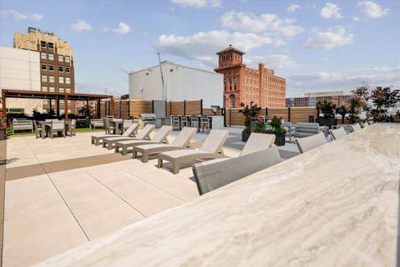 Rooftop terrace at Sky on Main featuring lounge chairs, dining areas, and panoramic views of Downtown Kansas City.