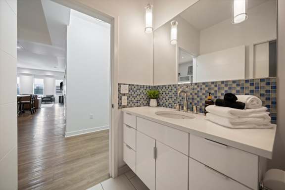Modern bathroom vanity area in a short-term rental apartment at Sky on Main with stylish fixtures, storage cabinetry, and fresh linens.