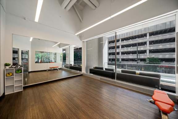 Bright yoga studio at Sky on Main featuring floor-to-ceiling windows, mirrored walls, wellness equipment, and views of Downtown Kansas City.