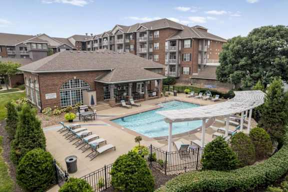 Elevated view of the outdoor swimming pool and sundeck at The Claremont Apartments featuring lounge chairs and poolside amenities.