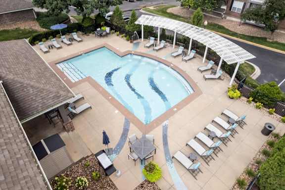 Overhead view of the resort-style swimming pool, shaded seating area, and pool deck at The Claremont Apartments in Overland Park, KS.