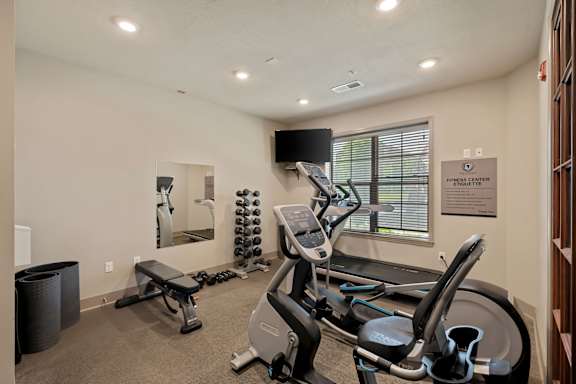 Fitness center at The Dorset with cardio machines, free weights, and workout bench