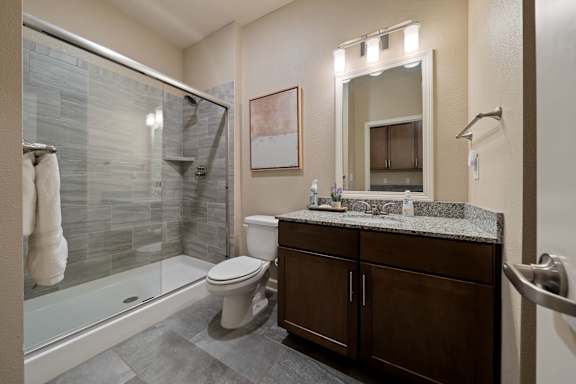 A bathroom with a toilet, sink, and a glass shower stall.