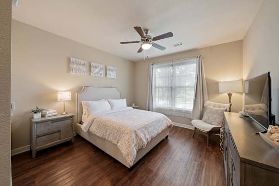 Guest suite bedroom at The Dorset featuring a queen bed, nightstand, window with natural light, and wood-style flooring