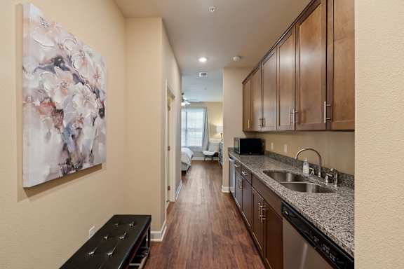Guest suite kitchenette at The Dorset with granite countertops, wood cabinetry, sink, and appliance space
