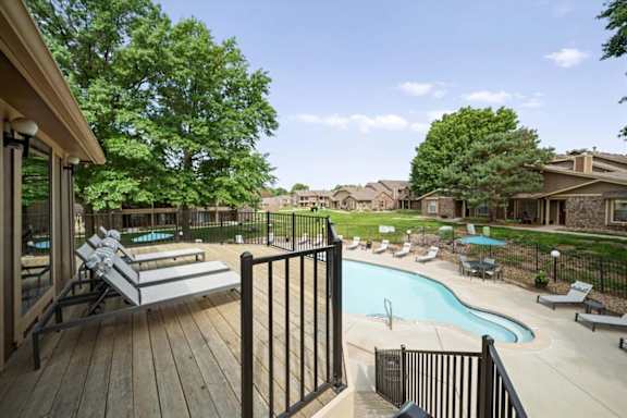 A pool area with a deck and lounge chairs.